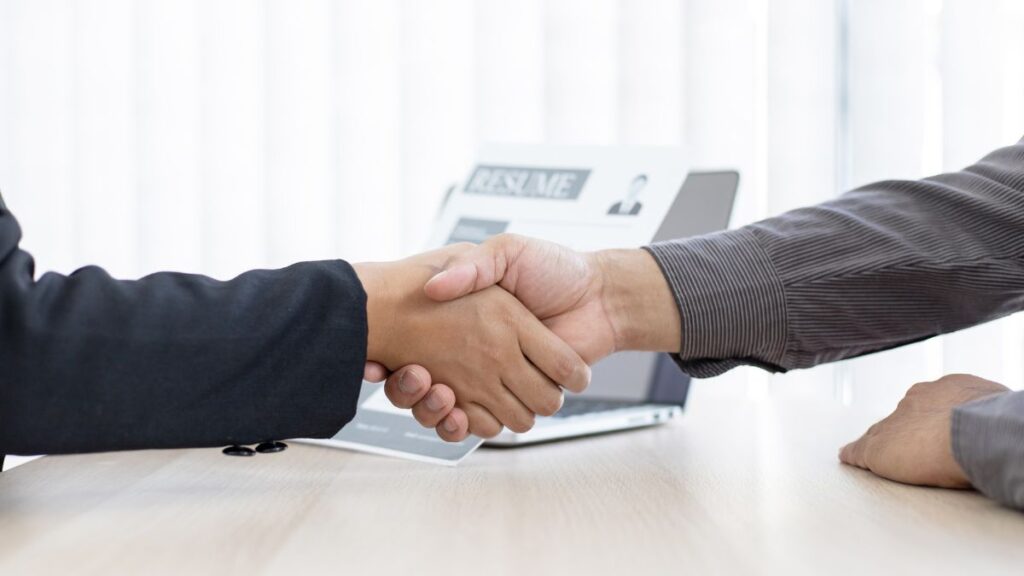 Two People Shaking Hands At A Desk