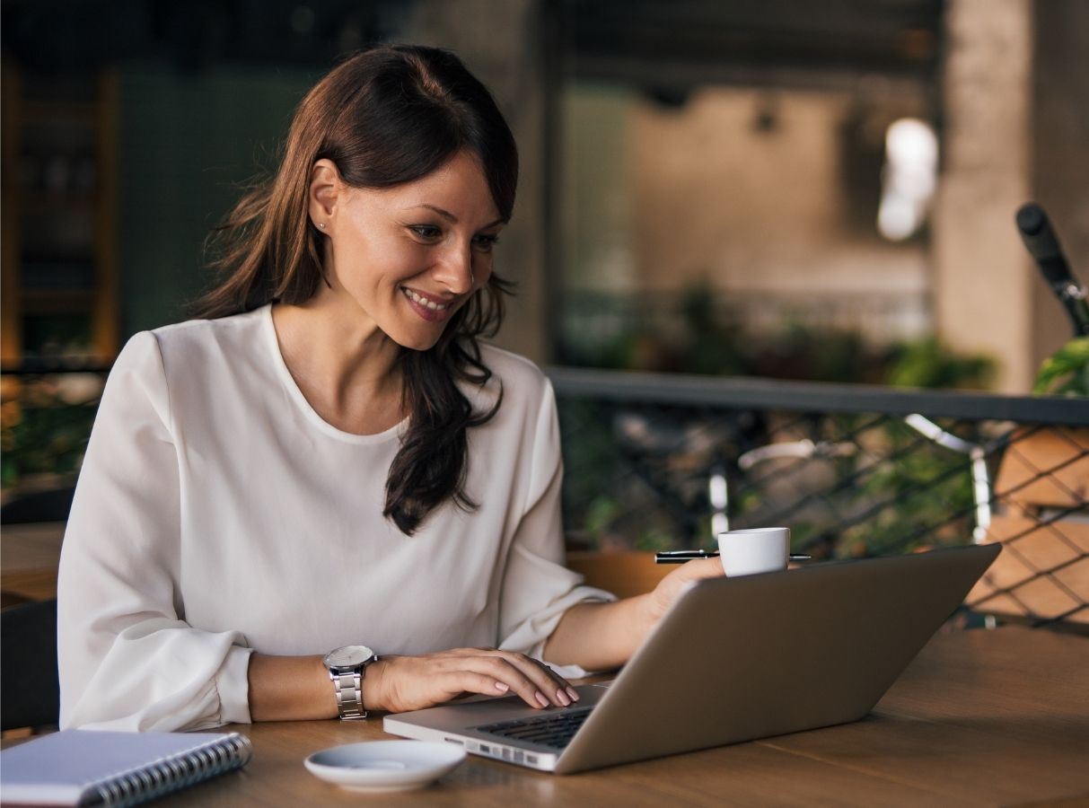 Woman Smiling While Working On A Laptop