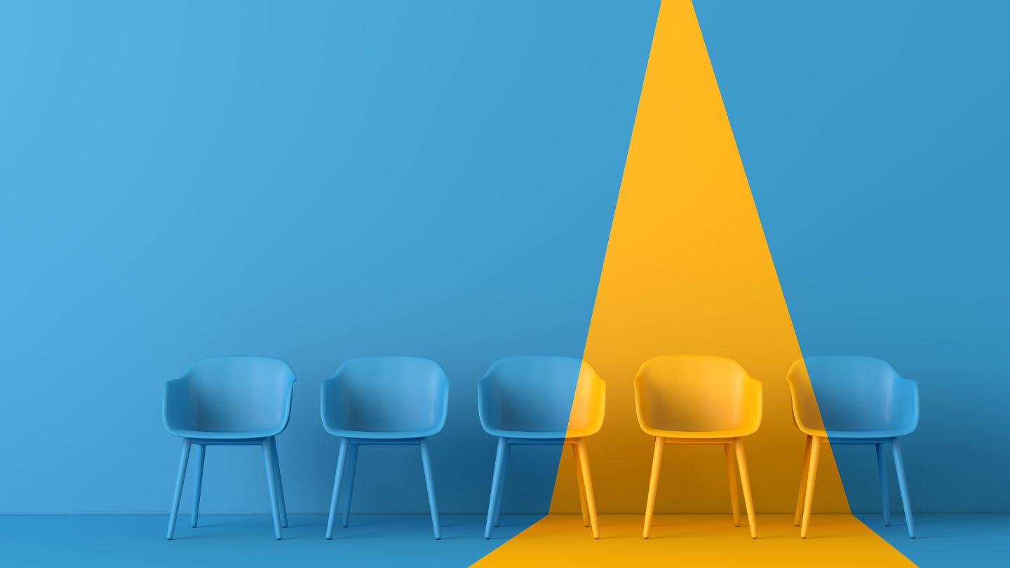 Blue chairs with one spotlighted in yellow.