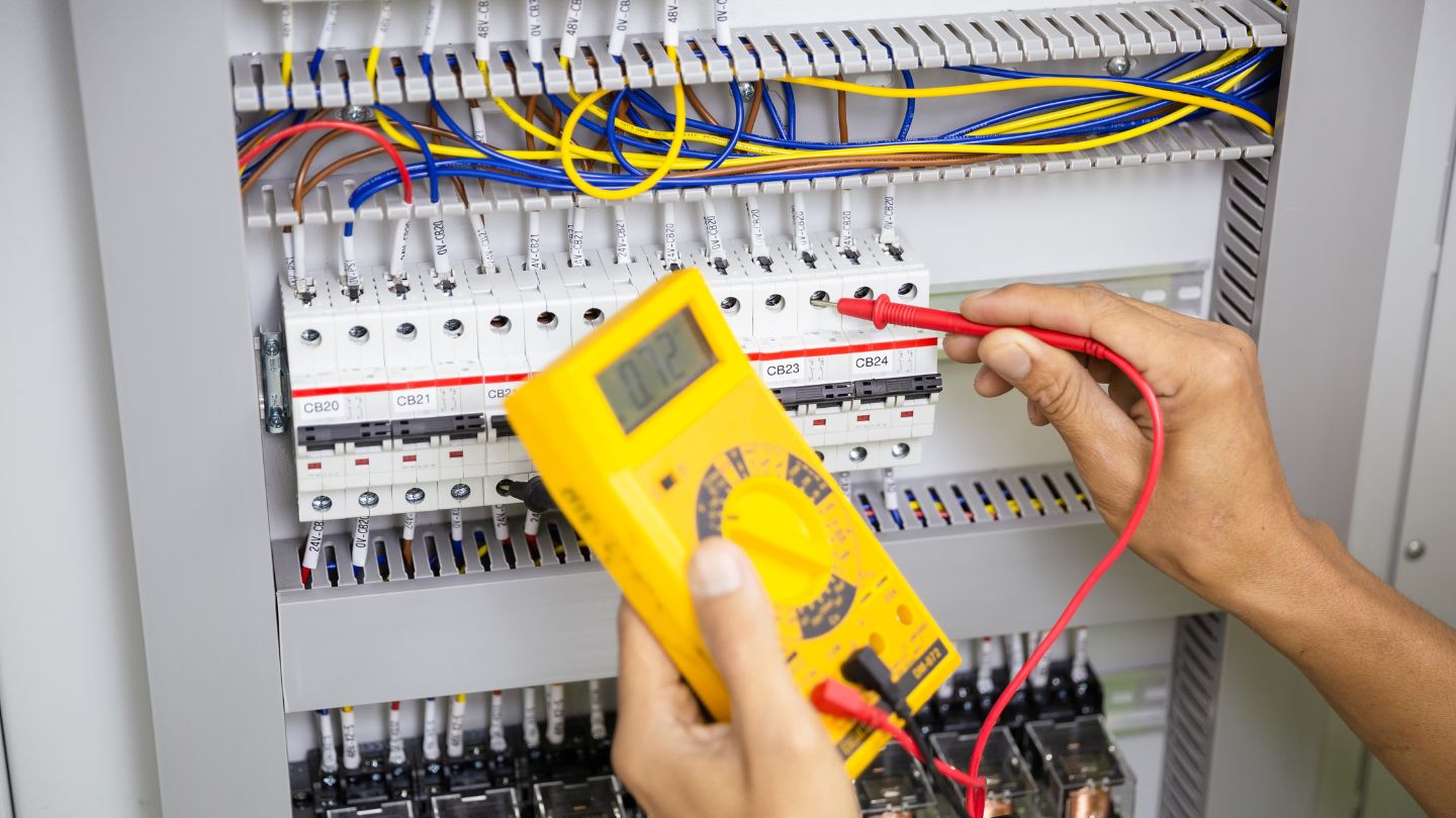 Person using multimeter on electrical panel.
